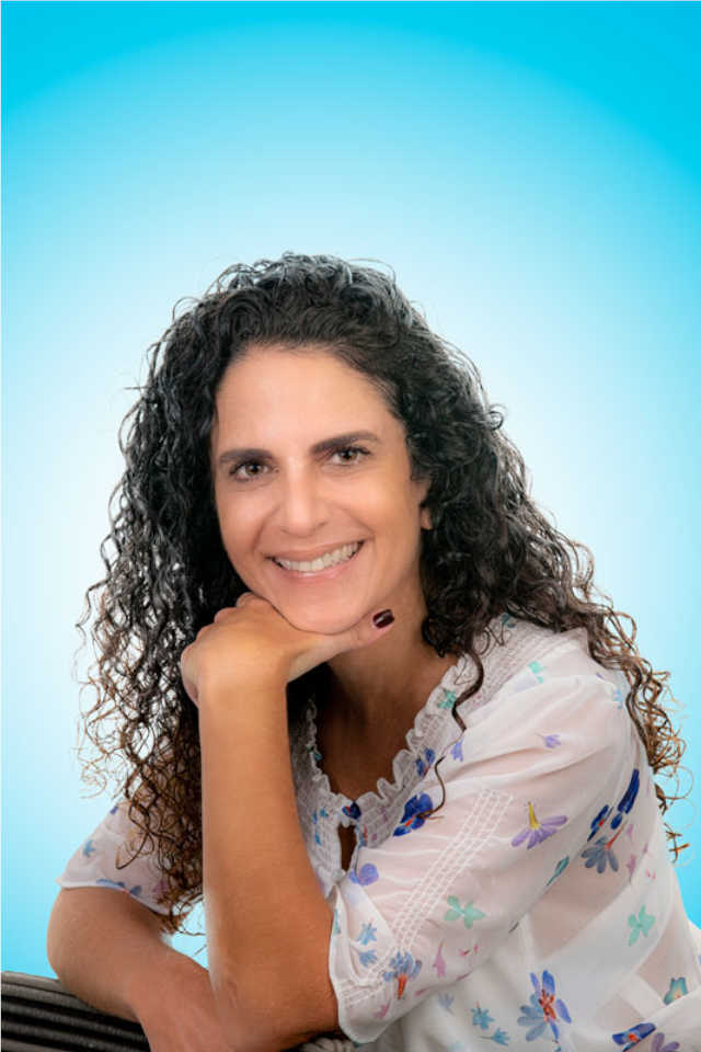 mujer sonriente con la mano en la quijada cabello suelto en fondo azul claro